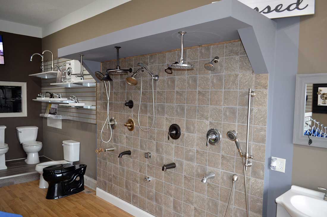 Shower fixtures and bath hardware on a tiled display wall, the kind fitted during a shower or tub installation in Wake Forest, NC
