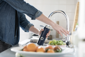 man filling up water bottle with tap water