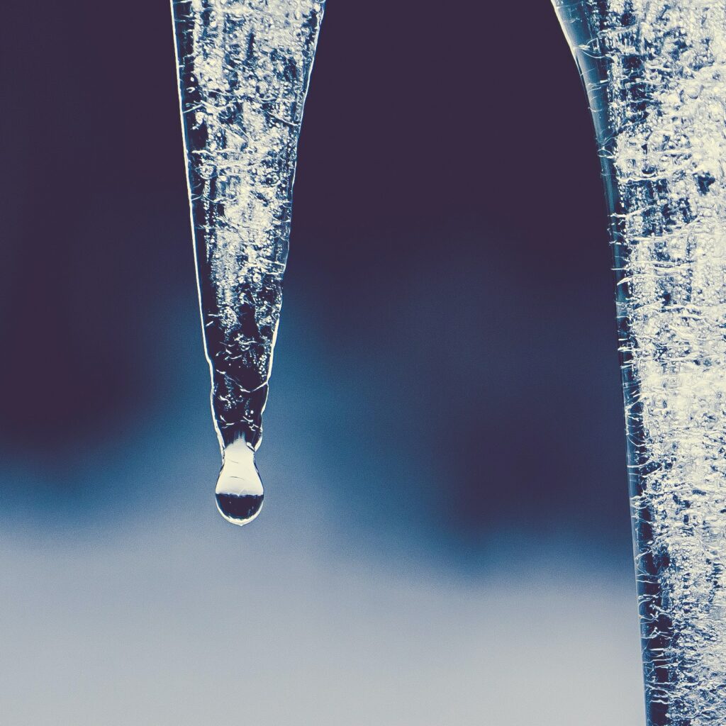 Meltwater dripping from an icicle, the thaw after a hard freeze that reveals burst pipes on emergency plumbing calls in Wake Forest, NC