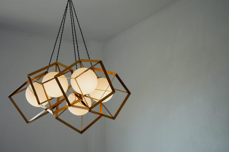 A round lamp with a rectangular iron frame suspended from the ceiling, illuminating in gold. Interior concept.