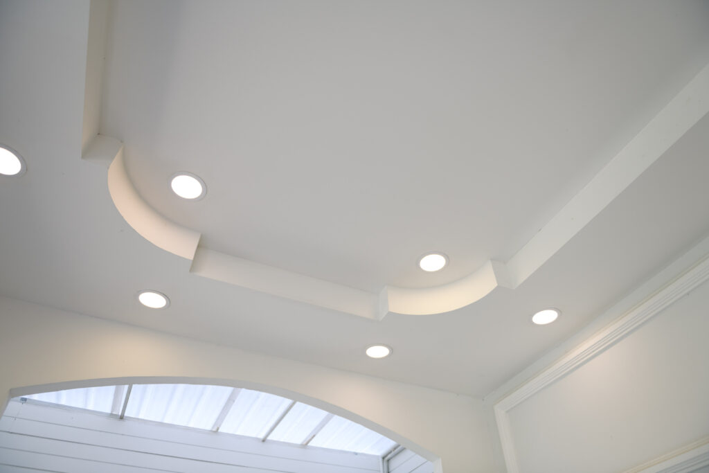 ceiling with halogen spots lamps and drywall construction in empty room in exhibition hall or house. Stretch ceiling white and complex shape.