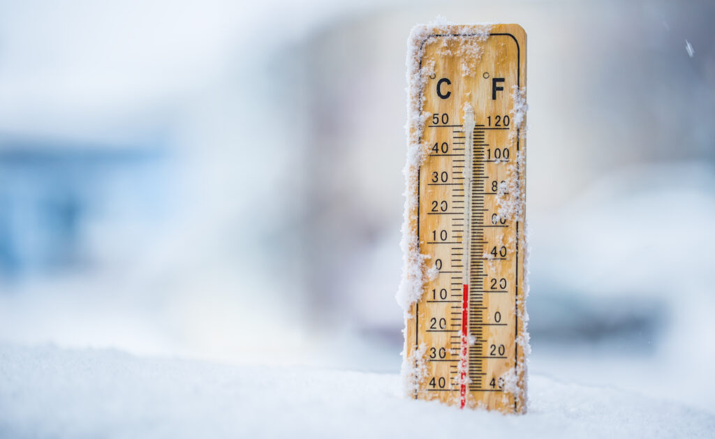 Thermometer on snow shows low temperatures in celsius or farenheit.